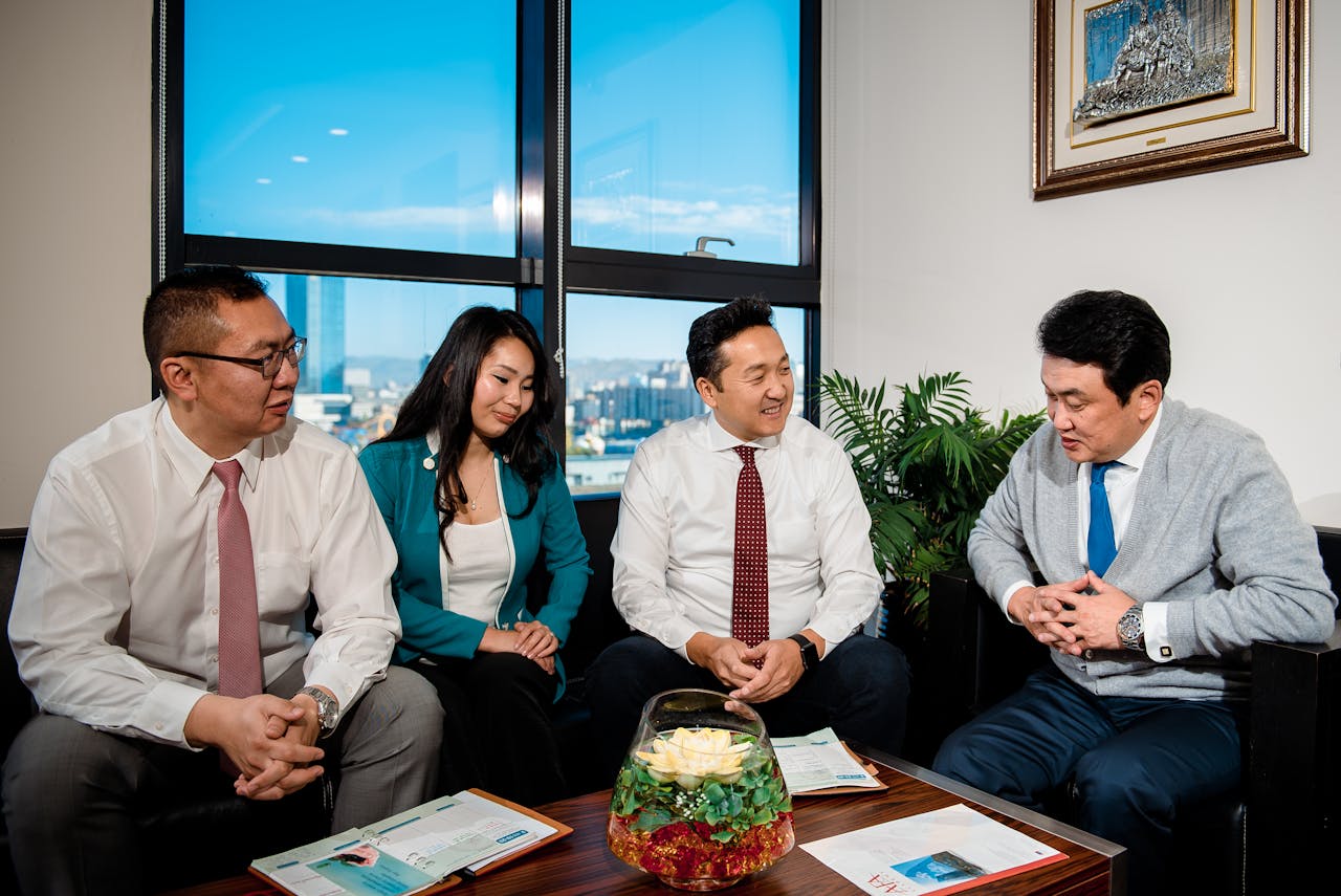 A group of business professionals engaging in a cheerful meeting in a modern office setting.